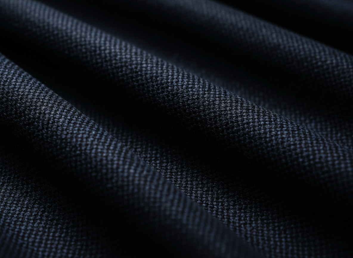 Macro photograph of premium women's woven fabric in deep charcoal and navy tones with subtle sheen.